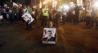 Mursi supporter holds a poster and sits at a street during an anti-army rally in Cairo