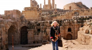 Heide with a backdrop of excavated ancient shops, doors to commercial spaces, and residences;  the important Temple of Zeus and Roman amphitheater on the hilltop.